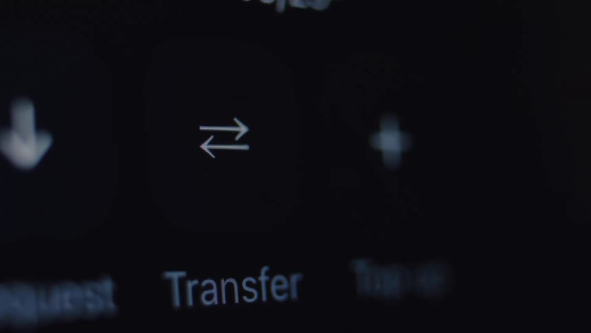 Macro view of a finger tapping the transfer button on a digital banking application