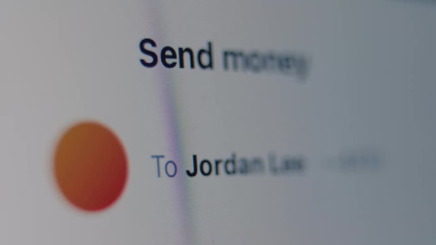 Macro shot of a financial app on a digital screen, showing a transfer to a contact named Jordan Law