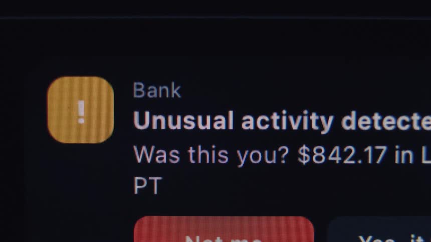 A close-up macro shot of a bank's 'Unusual activity detected' fraud alert on a digital screen