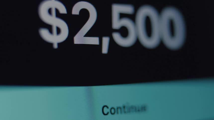 Extreme close up of a user sending a $2,500 digital money transfer on a screen, showing the amount being typed and the confirmation