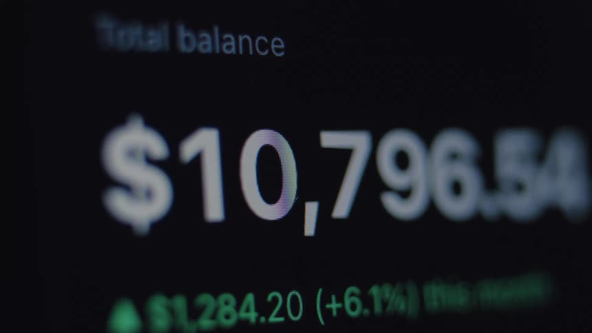 A macro view of a financial app shows a total balance in US dollars rapidly decreasing on a digital screen