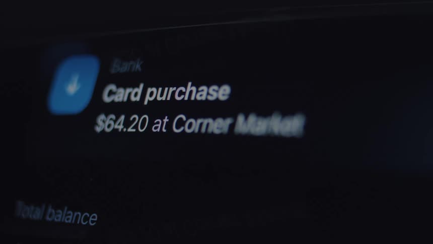 Close-up of a smartphone screen showing a notification alert from a banking app about a recent card purchase