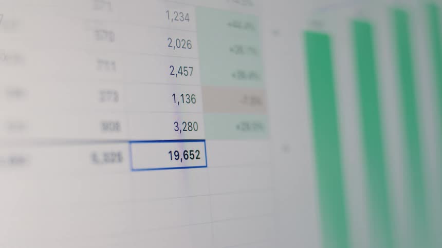A person enters numbers into a spreadsheet on a computer screen, culminating in a final total