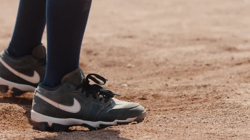 Close-up of a baseball player's cleats shifting and kicking up dust on the baseball diamond in slow motion