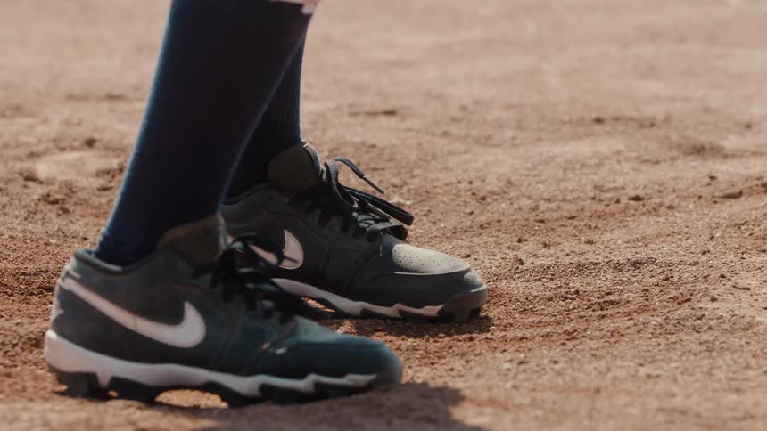 A baseball player's cleats dig into the dirt of the infield in slow motion