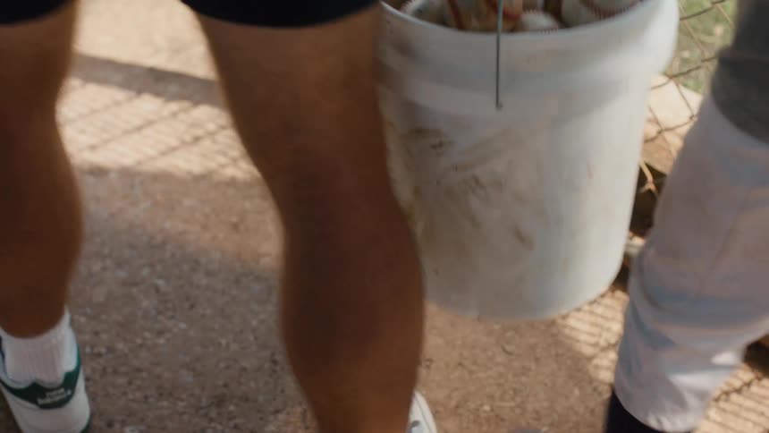 A man reads a heartfelt note left on a bucket of free baseballs and walks away with his son in slow motion