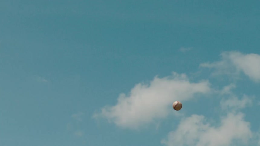 A baseball soars through the clear blue sky in super slow motion