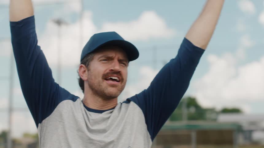 A baseball player with a mustache throws a ball and then celebrates a big play with his hands in the air in slow motion