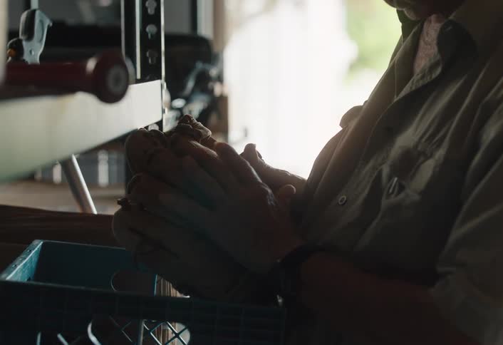 A senior man in his workshop gently holds a cherished old baseball glove, reminiscing about the past