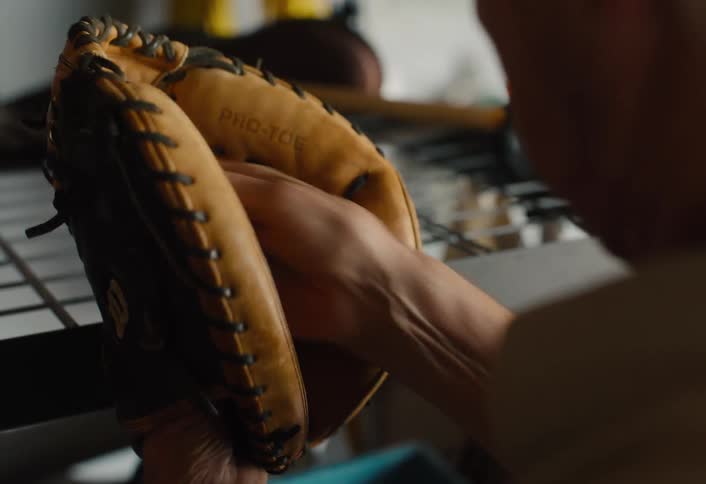 An elderly man pulls his well-worn baseball glove out of a storage bin, reminiscing about past games