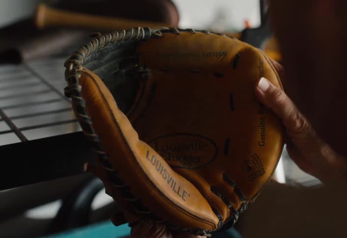 Close up of a man's hands pulling out an old leather baseball glove and conditioning it, reminiscing about the glory days