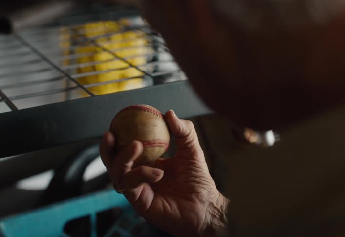 Close up on the weathered hands of an elderly man as he fondly remembers his past while holding an old baseball