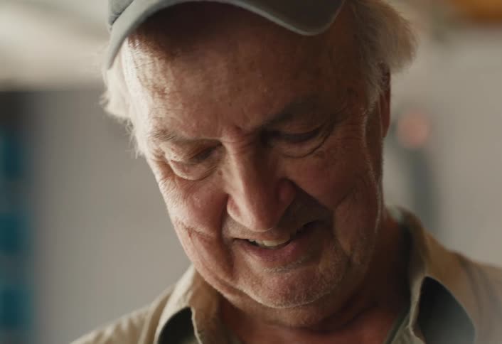A sentimental elderly man in a cap holds an old baseball glove, smiling fondly as he remembers his past