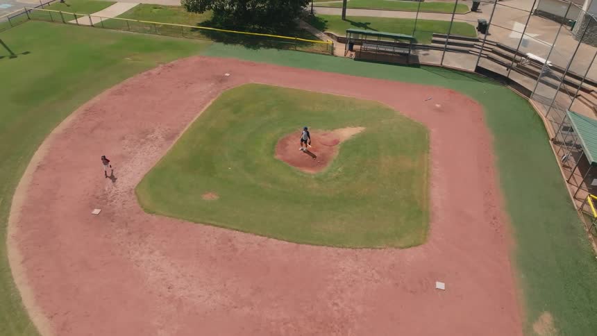An inspiring aerial view shows a father pitching to his young son who hits a home run and joyfully runs the bases