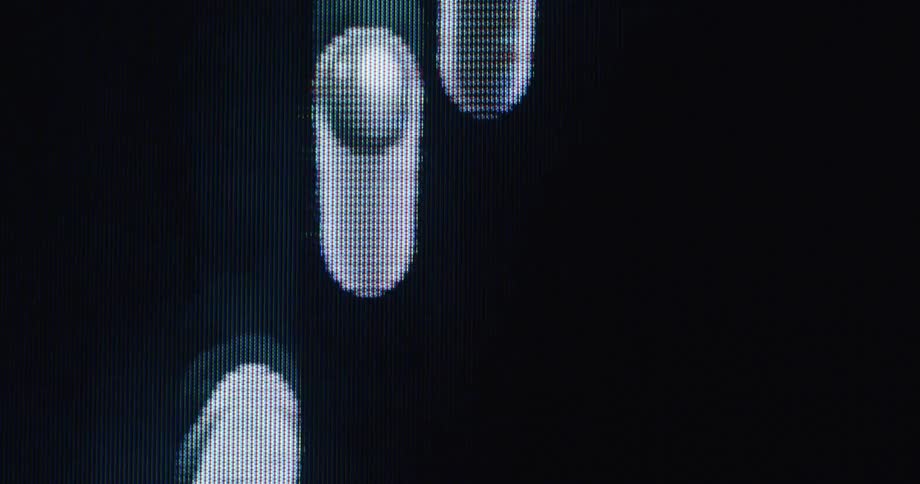 Hypnotic white pixelated shapes flow in abstract patterns across a dark digital screen in a macro view