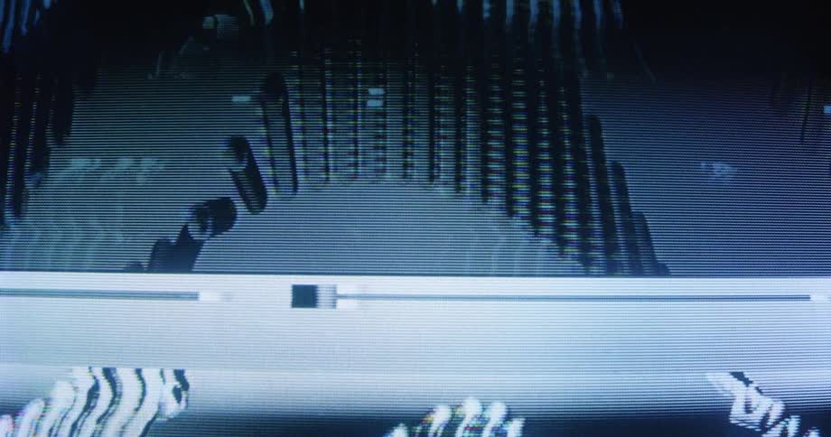 A close-up of a CRT screen displays abstract, wavy, and glitching blue and white patterns
