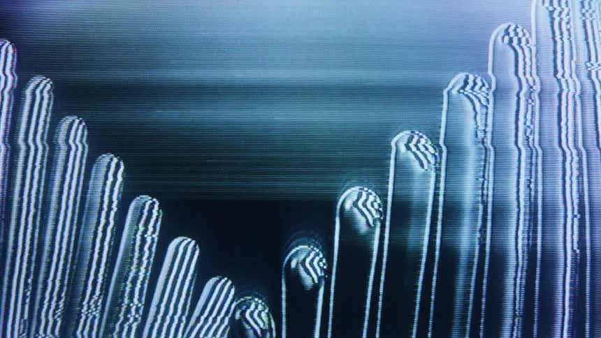 An abstract digital image warps and distorts on a CRT screen, creating flickering static and glitchy vertical lines