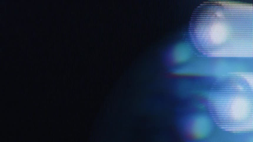 An extreme close-up reveals the individual pixels of a screen displaying abstract, glowing, and shifting horizontal light forms
