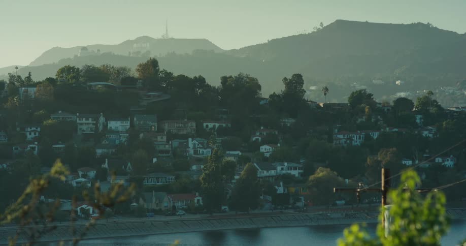A static wide shot of the Hollywood Hills and Hollywood sign overlooking a reservoir on a hazy morning