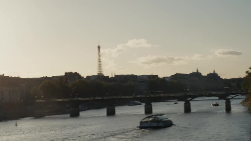 A shaky, artistic transition reveals the Paris skyline with the Eiffel Tower and a boat on the Seine River at golden hour