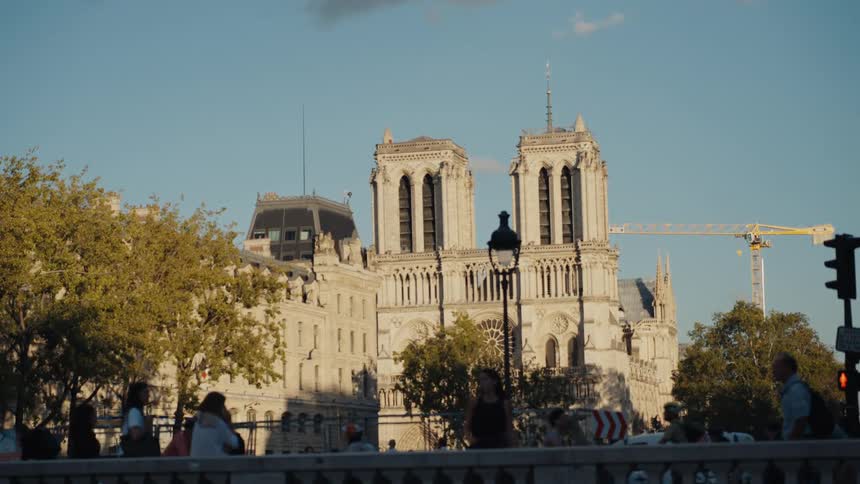 The historic Notre Dame Cathedral stands tall in Paris at sunset, with busy street life unfolding in the foreground