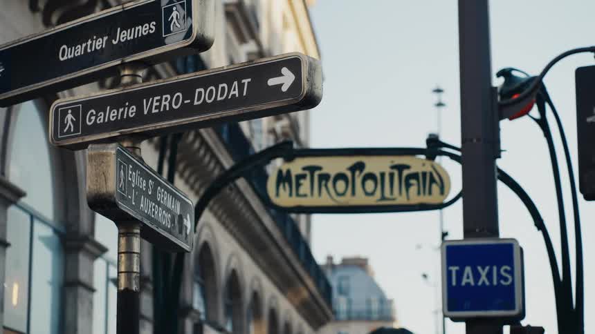 Iconic Metropolitain sign and street direction signs on a classic Parisian street with a rack focus effect