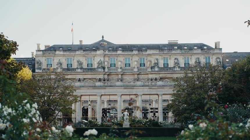 A static shot of a historic French government building or palace, viewed from across its manicured rose garden
