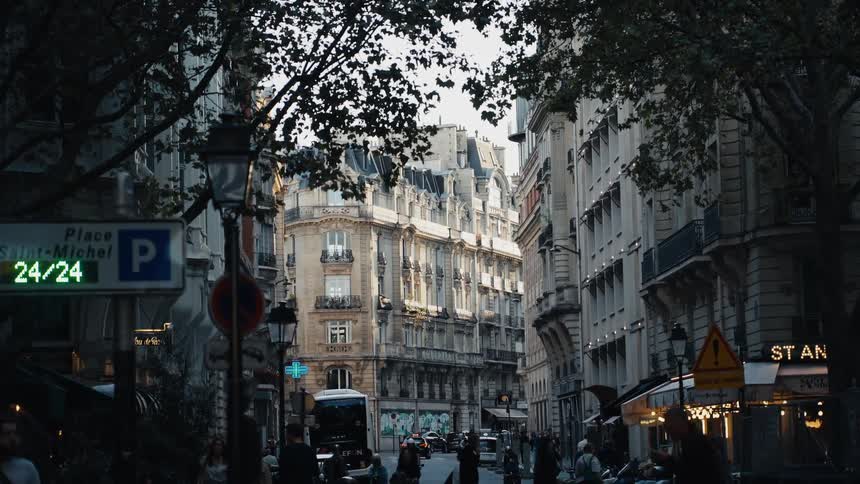 Bustling city life unfolds on a classic Parisian street near Place Saint-Michel as the afternoon light fades