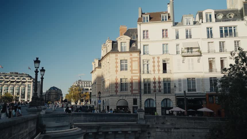 A picturesque street corner in Paris, with classic architecture and pedestrians enjoying a sunny day from a bridge