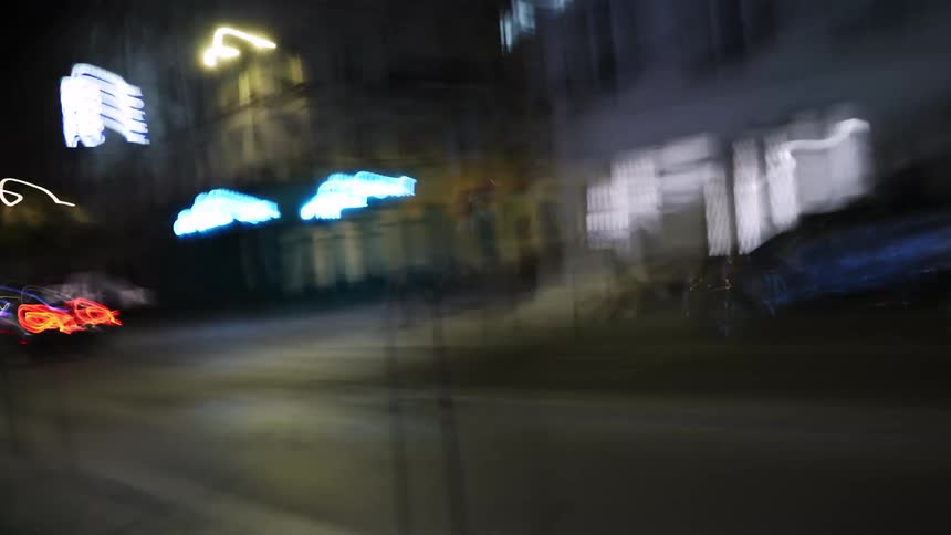 A dizzying first-person perspective walk through city streets at night, with long exposure creating abstract trails of colorful lights