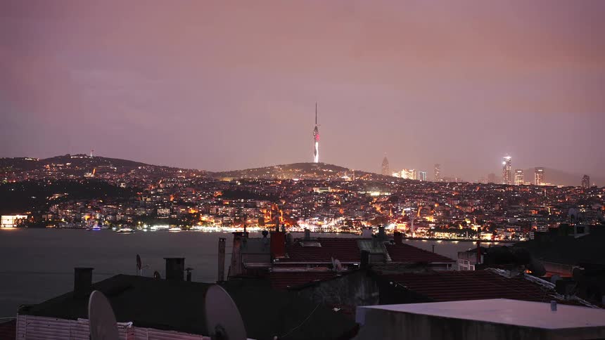 A mesmerizing timelapse captures the Istanbul skyline transitioning from a cloudy purple dusk to a vibrant, illuminated night over the Bosphorus Strait