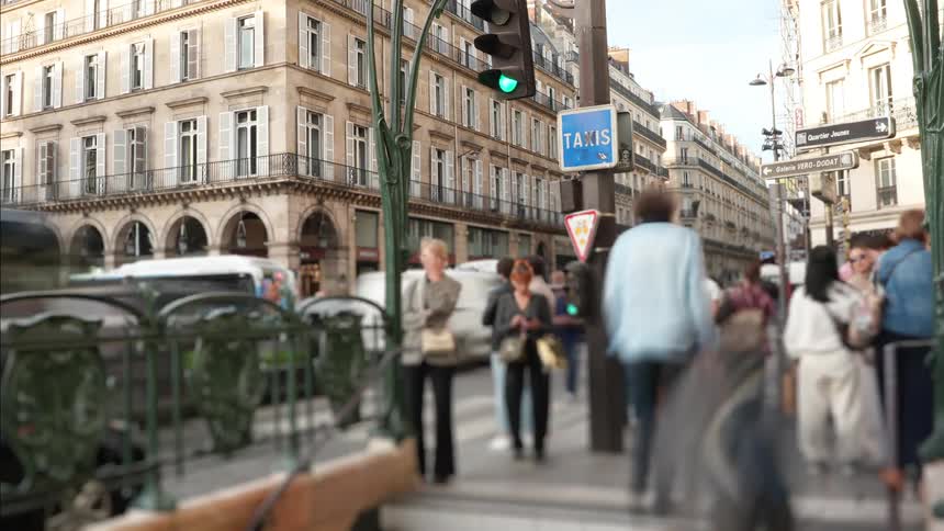 A time-lapse view from a Paris Metro entrance captures the anonymous, bustling crowds and traffic on a city street