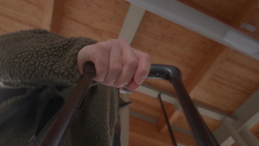 A low-angle close-up shot of a man's hand on his luggage handle as he waits patiently at a modern terminal