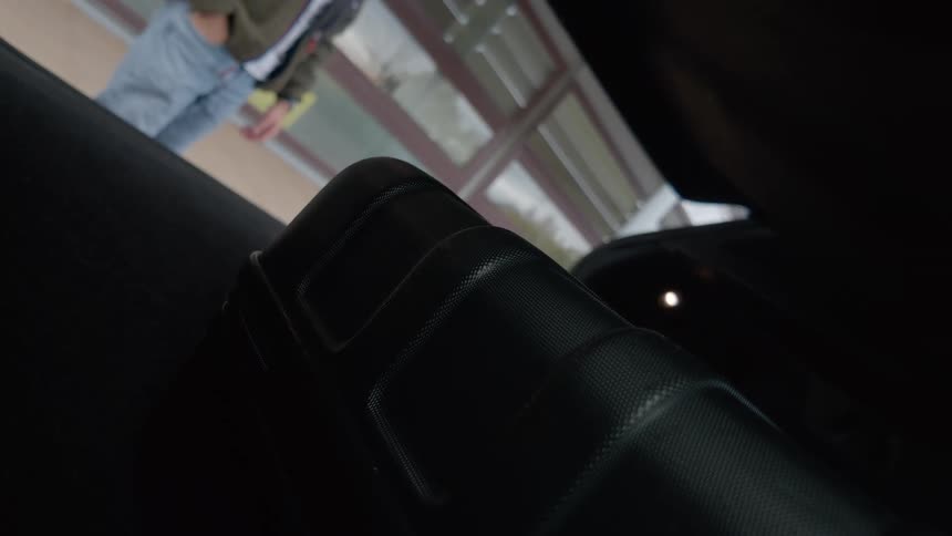 A man loads his luggage into the trunk of his car before closing it, filmed from a unique perspective inside the trunk
