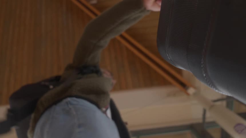 Low angle point of view shot from inside a bin shows a man throwing a large black suitcase into the trash