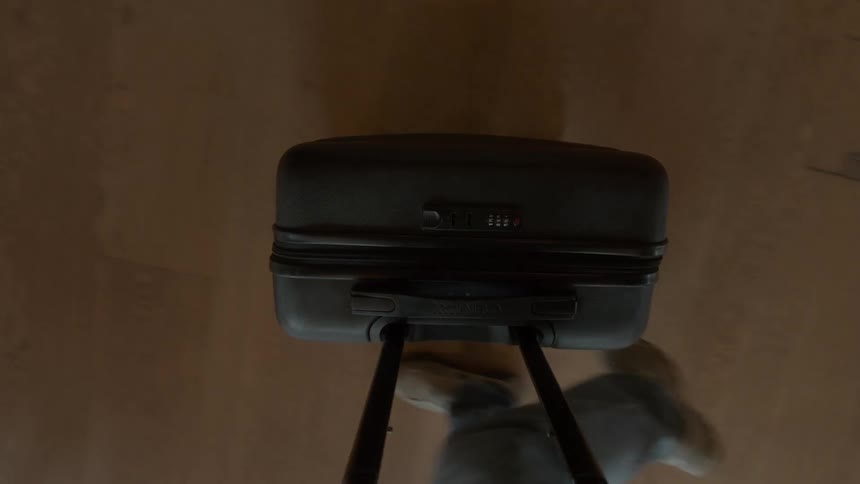 First-person perspective of a person walking with rolling luggage across a wooden floor