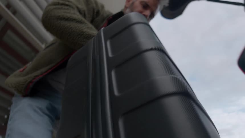 Point-of-view from inside a car trunk as a man unloads his black suitcase and walks away
