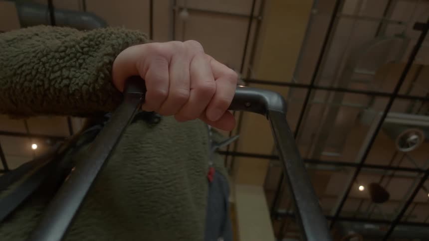 Slow-motion, low-angle shot from a suitcase looking up at a man walking through a modern terminal