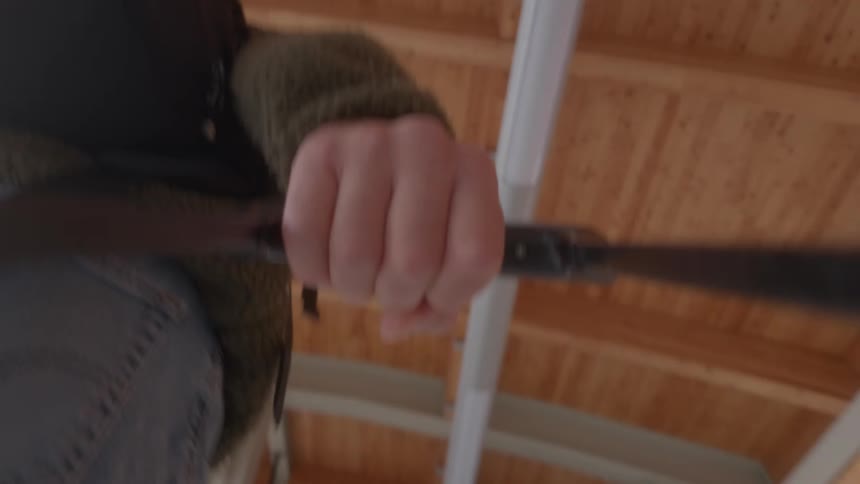 A low-angle, barrel-mounted camera view shows a person's hand gripping a lever-action rifle while walking through a building