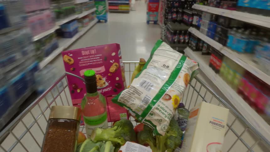 A point-of-view hyperlapse of a shopping cart full of groceries being pushed through the aisles of a supermarket
