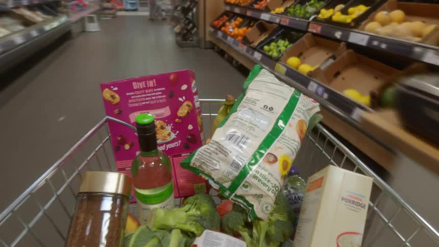 Time-lapse point-of-view shot of a shopping cart filled with groceries speeding through the aisles of a supermarket