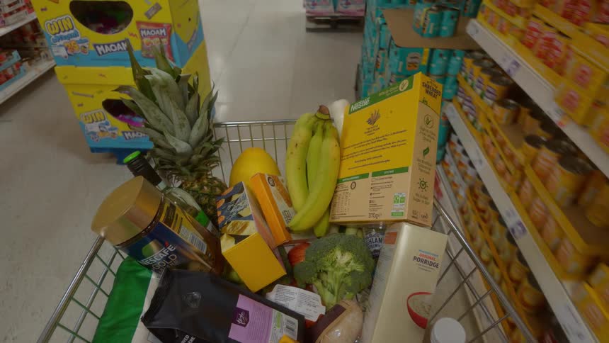 Point of view from a shopping cart full of groceries being pushed through the aisles of a supermarket