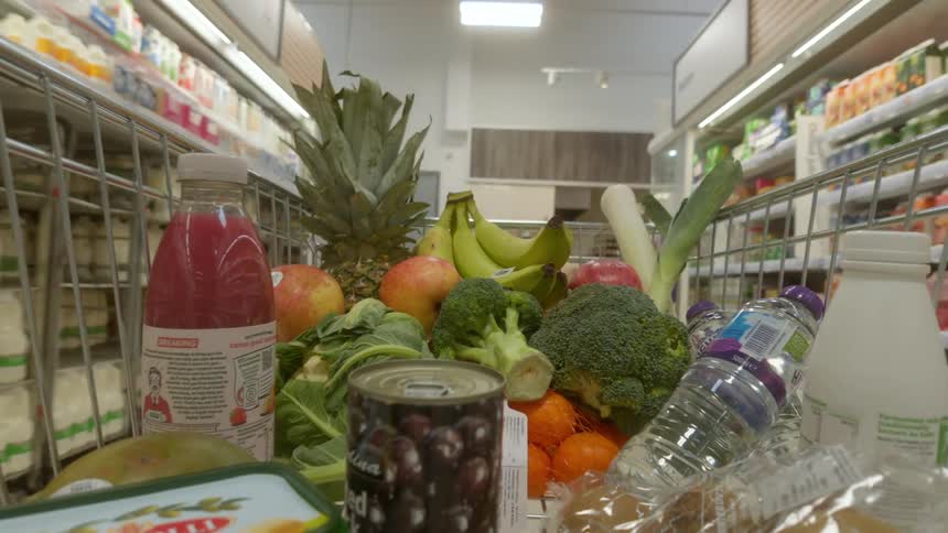 Point-of-view shot from a shopping cart full of healthy groceries moving through the aisles of a supermarket