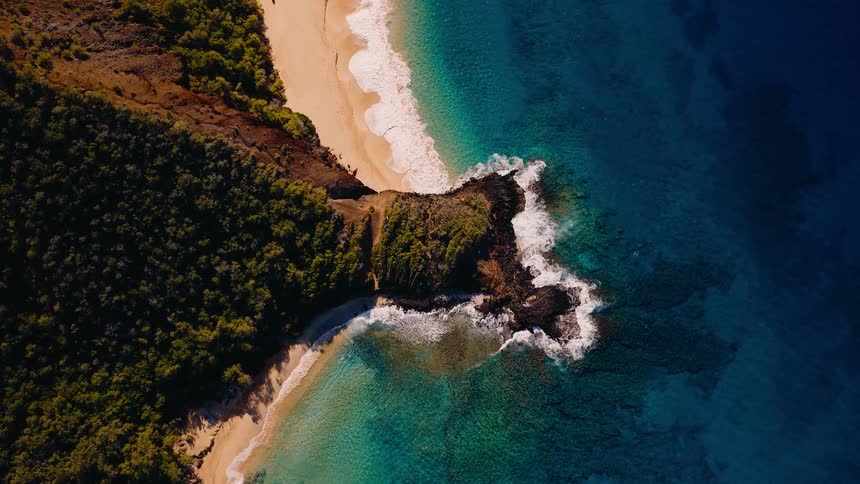 Mesmerizing top-down aerial view of a tropical island beach with turquoise water and a volcanic rock point