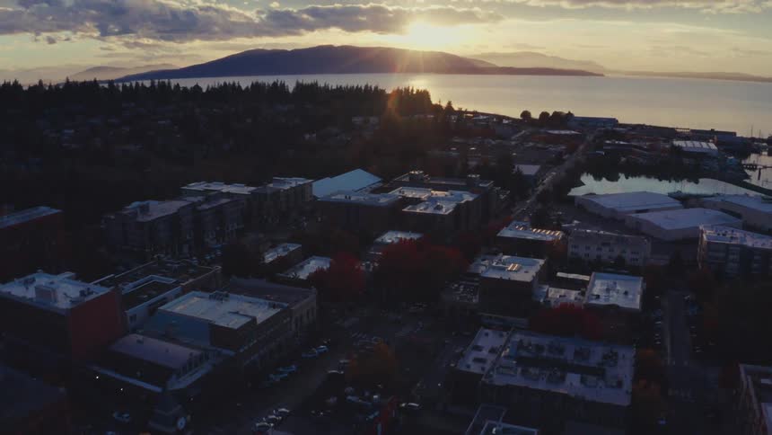 Aerial view of a coastal town with a bay and mountains in the background at sunset
