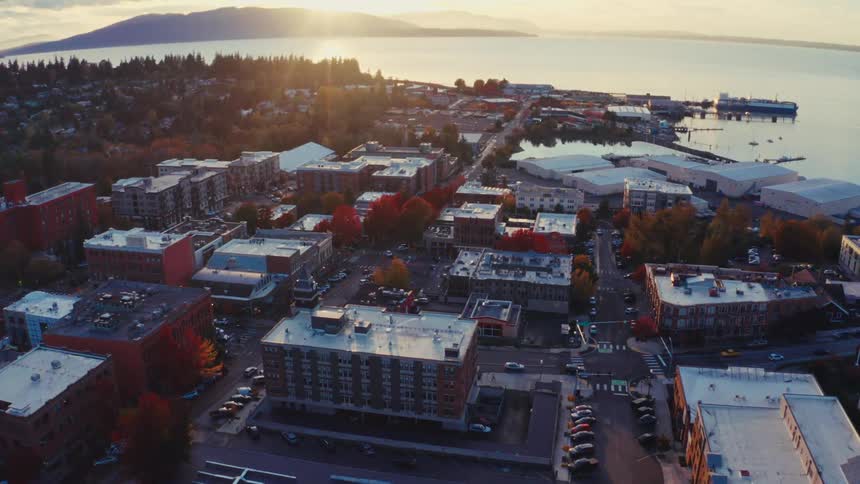 A stunning aerial view rises over a charming coastal town during a beautiful autumn sunset, revealing the tranquil harbor and distant hills