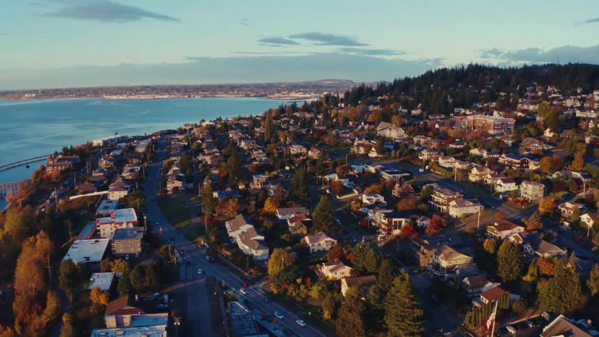 A beautiful aerial view of a coastal town with colorful autumn trees nestled along the waterfront at sunset