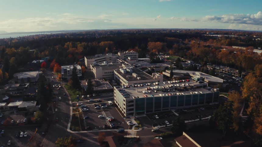 A slow push-in aerial view of a large hospital campus surrounded by a suburban town and beautiful autumn foliage