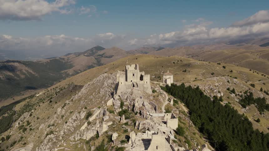 A stunning aerial view reveals the ancient ruins of Rocca Calascio castle perched atop a rocky mountain in Italy
