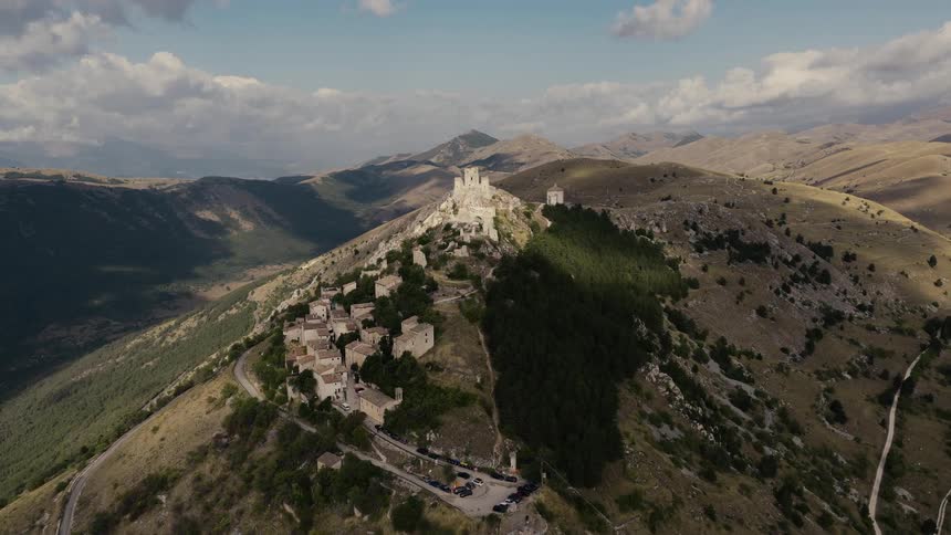 Majestic aerial pullback reveals the ancient fortress of Rocca Calascio and its village built on a remote mountain top in Italy